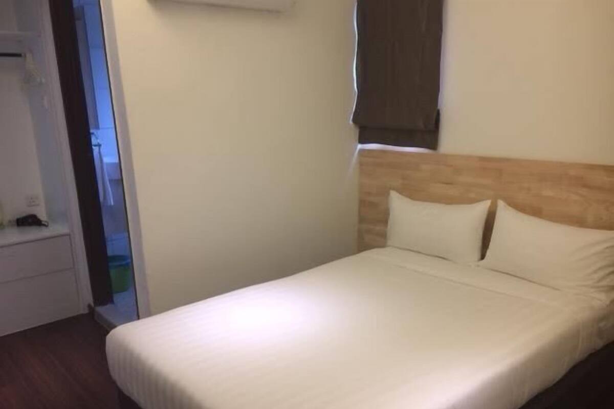 En pænt redt seng med hvide sengetæpper i et hotelværelse.