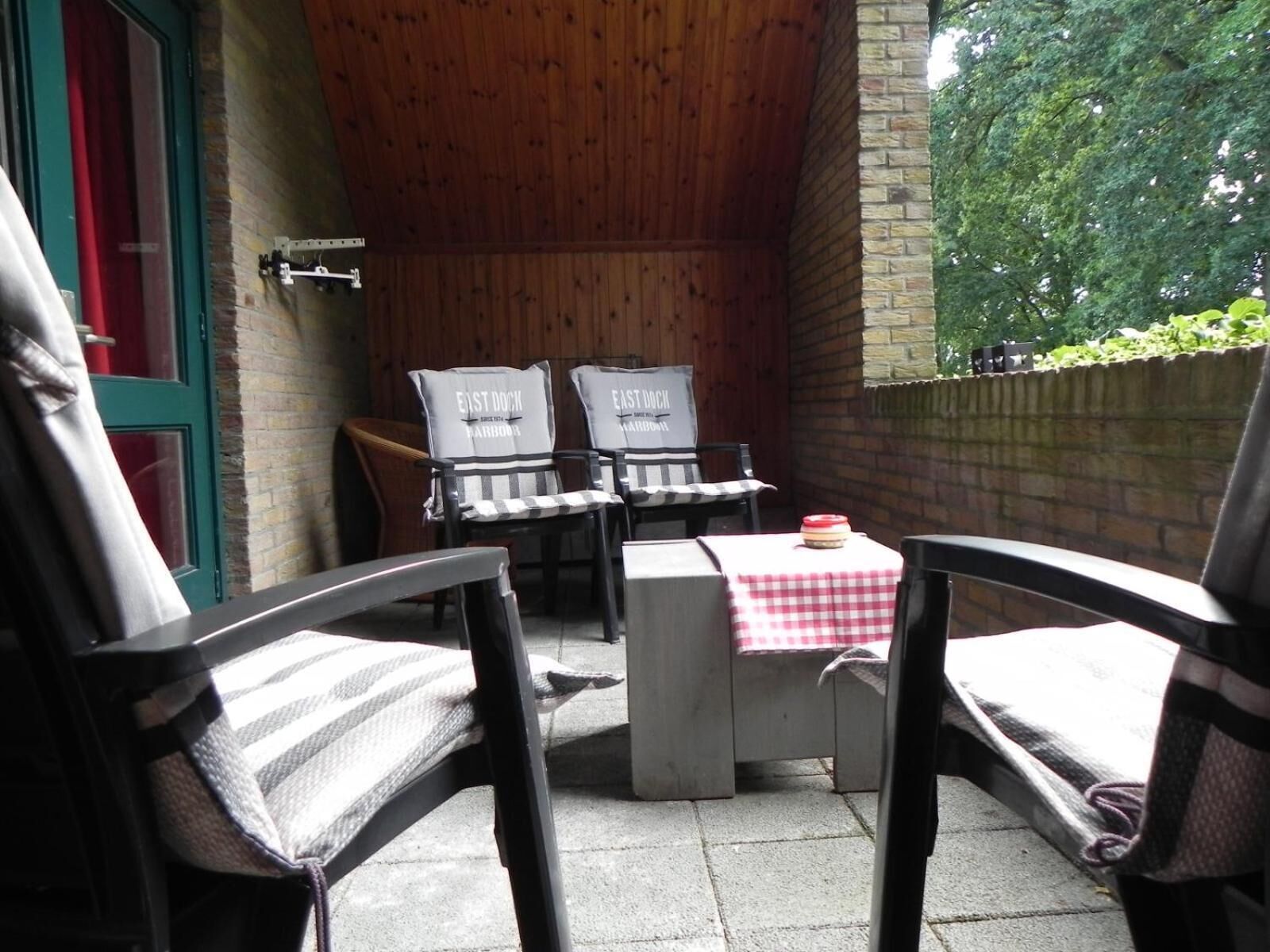 An outdoor patio area with two chairs labeled "EAST DOCK" and a table with a red and white checkered tablecloth.
