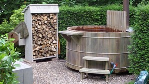 A wooden sauna structure with a firewood storage area and a hose for water. - B&B Op de Parkkamp (Havelte)