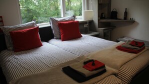 A hotel room with a large bed, striped bedding, red pillows, and a view of trees through the window. - B&B Op de Parkkamp (Havelte)