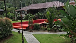 A pathway leading to a building with a tiled roof, surrounded by lush greenery and palm trees. - Red Moon Hideaway (Ko Chang)