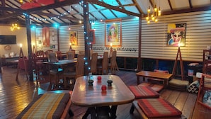 A cozy restaurant with wooden tables and benches, string lights, and artwork on the walls. - Red Moon Hideaway (Ko Chang)