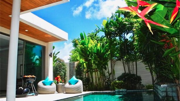 Uma casa moderna com piscina, rodeada por plantas tropicais exuberantes e um céu azul límpido.