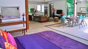 Quarto de hotel moderno com cama, área de refeições, cozinha e uma janela grande.