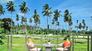 A balcony with wicker chairs and a small table, overlooking a lush landscape with palm trees and a clear sky. - Ka Villa Rawai : Peaceful 4 Bedrooms (Rawai)