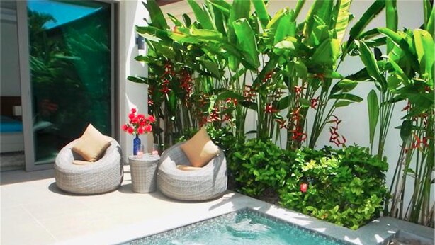 A swimming pool with two wicker lounge chairs and a small table with red flowers. - Ka Villa Rawai : Peaceful 4 Bedrooms (Rawai)