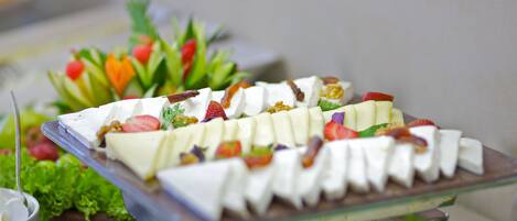 A buffet with various food items including fruits, vegetables, and cheese.