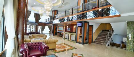 A spacious lobby with a high ceiling, a grand staircase, and a bar area.
