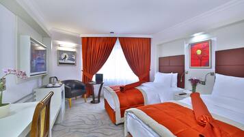 A hotel room with two beds, a desk, a chair, a TV, and a painting on the wall.