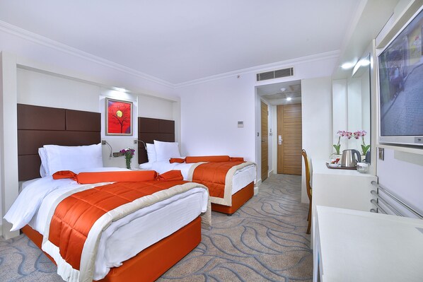 Une chambre d’hôtel avec deux lits, un bureau, une chaise, une télévision et une œuvre d’art rouge accrochée au mur.