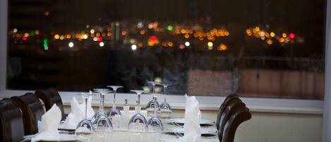 A table set for dining with a cityscape view through a window.