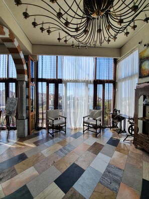 A spacious room with a large window, a chandelier, and a painting on the wall. - Warda وَرْدَة Lebanese Guesthouse (Zouk Mosbeh)