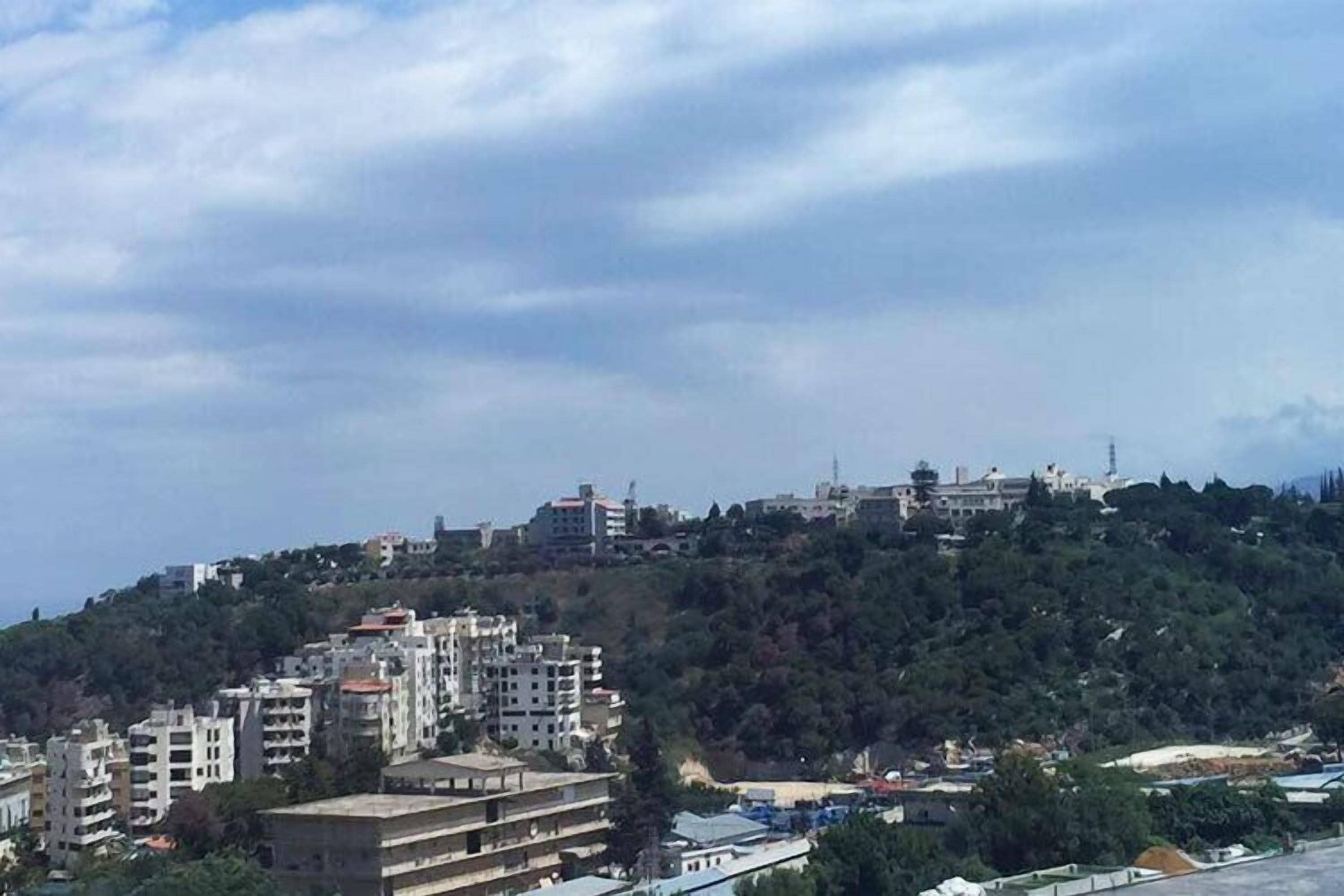 Una zona residencial en una ladera con edificios, algunos con balcones, bajo un cielo nublado.