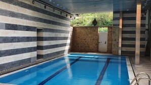 Una piscina interna con pavimento piastrellato e un murale colorato al soffitto.