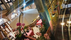 Atrio interno con un'area giardino centrale, posti a sedere e una scala con ringhiere decorate.