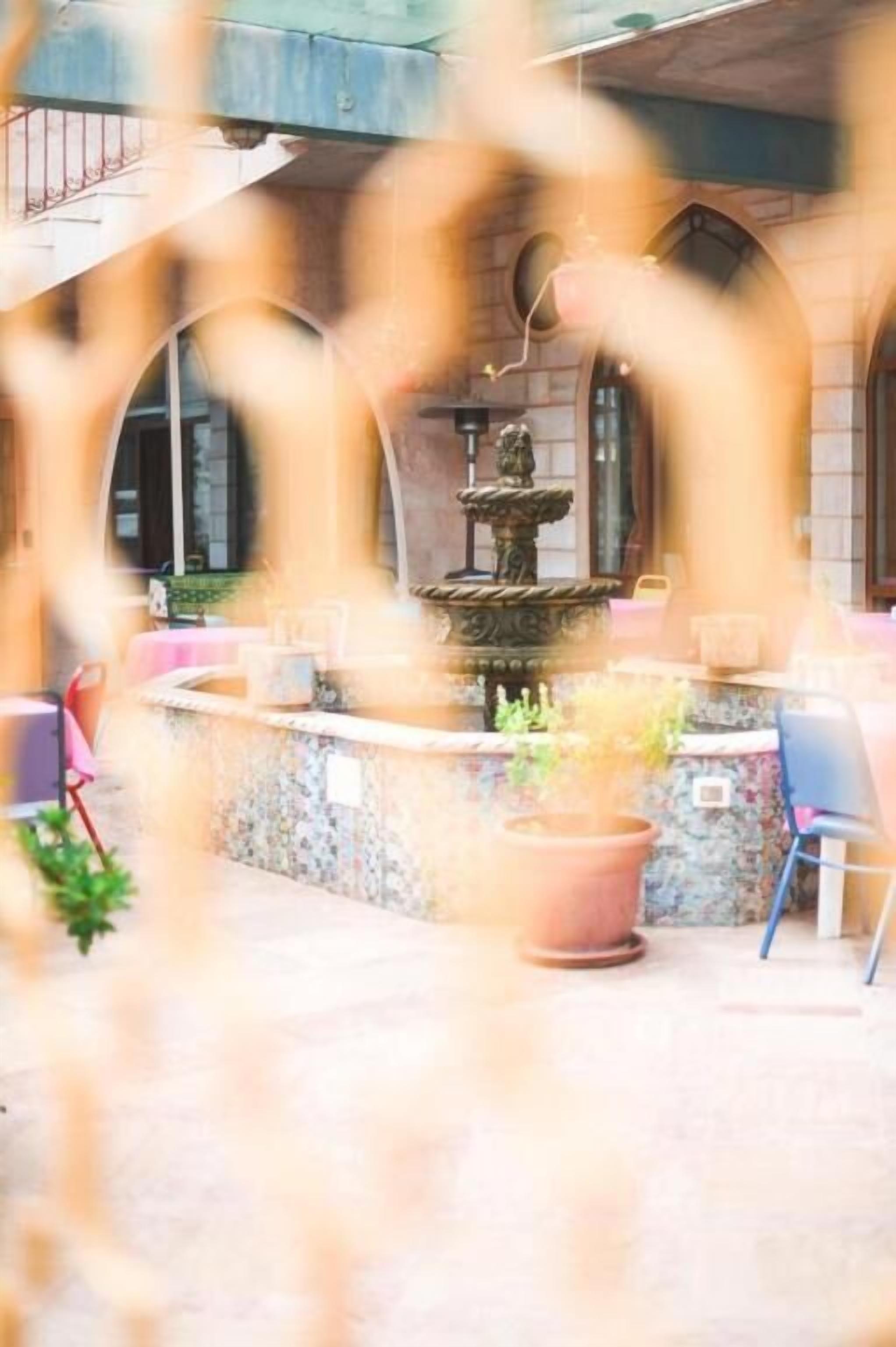 A courtyard with a fountain, seating area, and a building with arched windows.