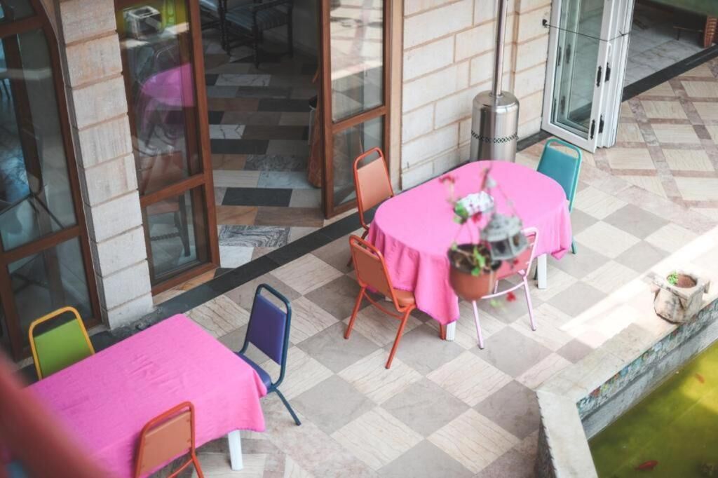 Un espacio al aire libre con mesas y sillas, piso de baldosas y una pequeña fuente de agua.