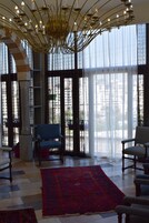 A spacious room with a large window, a red rug, and two chairs.