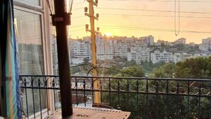 Una stanza con una grande finestra che si affaccia su una città al tramonto.