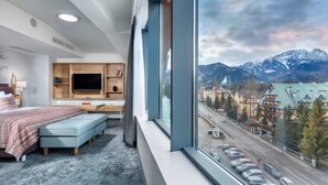 Une chambre d’hôtel moderne dotée d’une grande fenêtre, d’un lit, d’un bureau et d’une télévision.