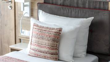 A bedroom with a bed, two pillows, a nightstand, and a wall with a floral pattern.