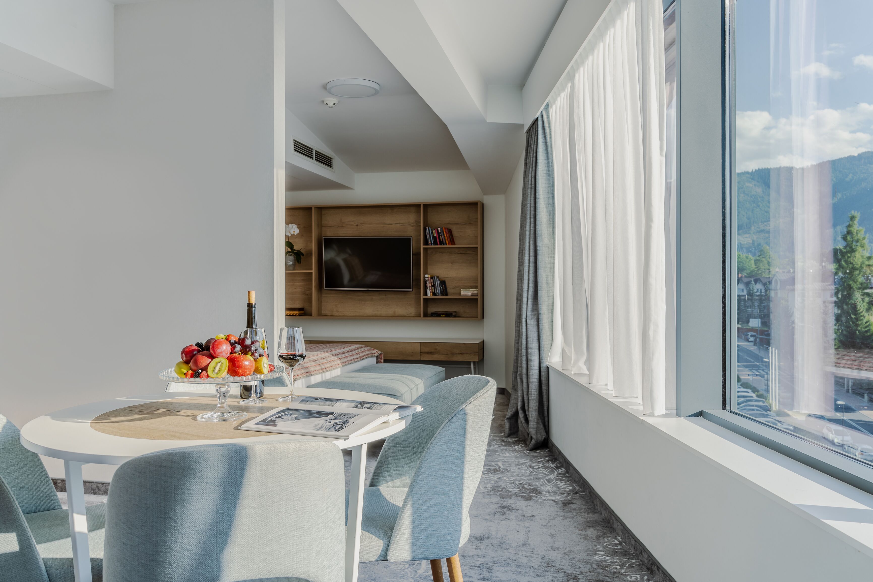 Un comedor moderno con una mesa redonda, sillas tapizadas en azul claro y un frutero sobre la mesa.