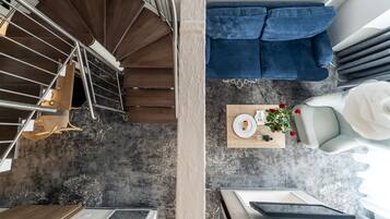 A modern kitchen with a spiral staircase, a dining area with a blue sofa, and a wooden table with a plate and flowers.