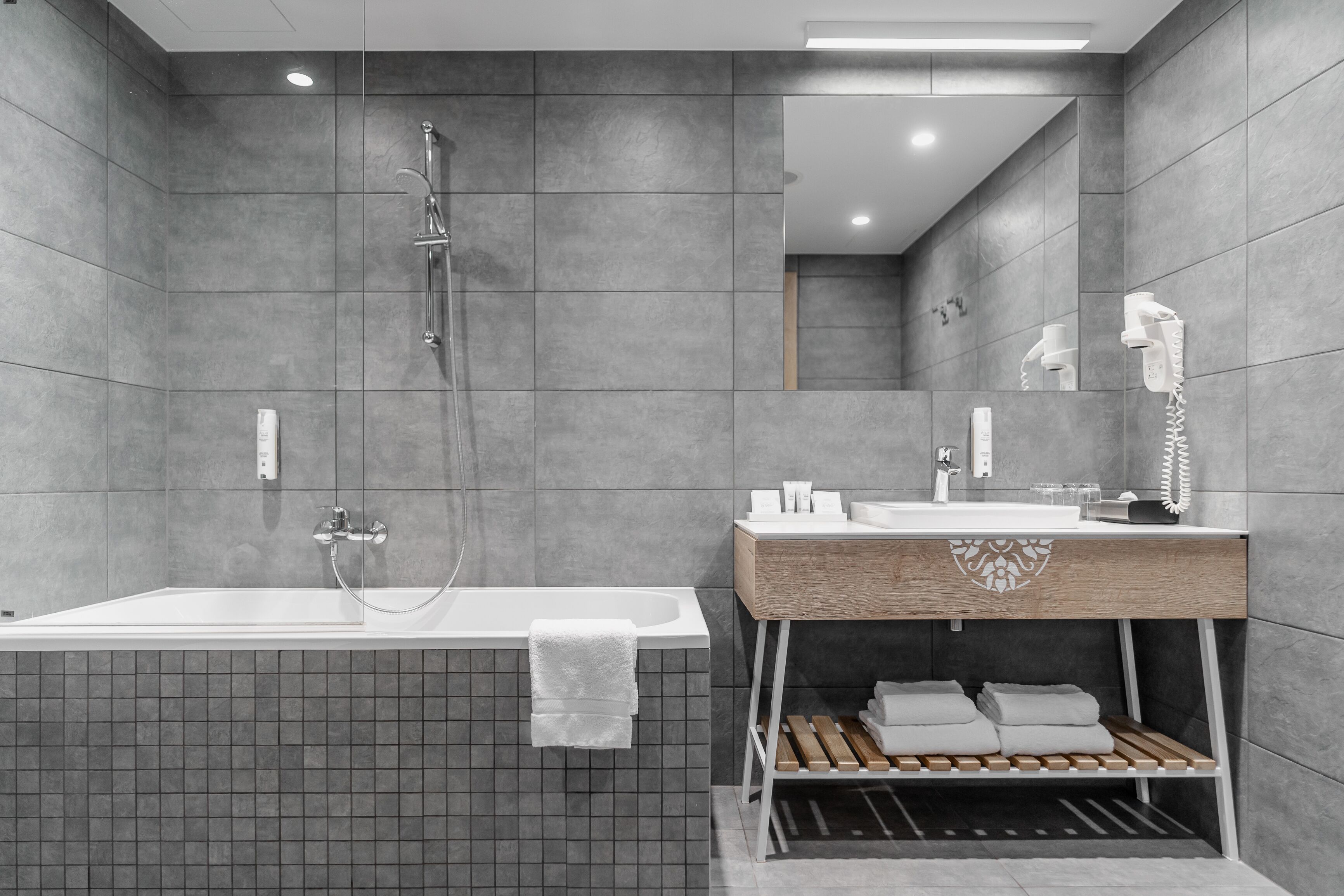 Een moderne badkamer met een bad, een douche en een wastafel met spiegel.