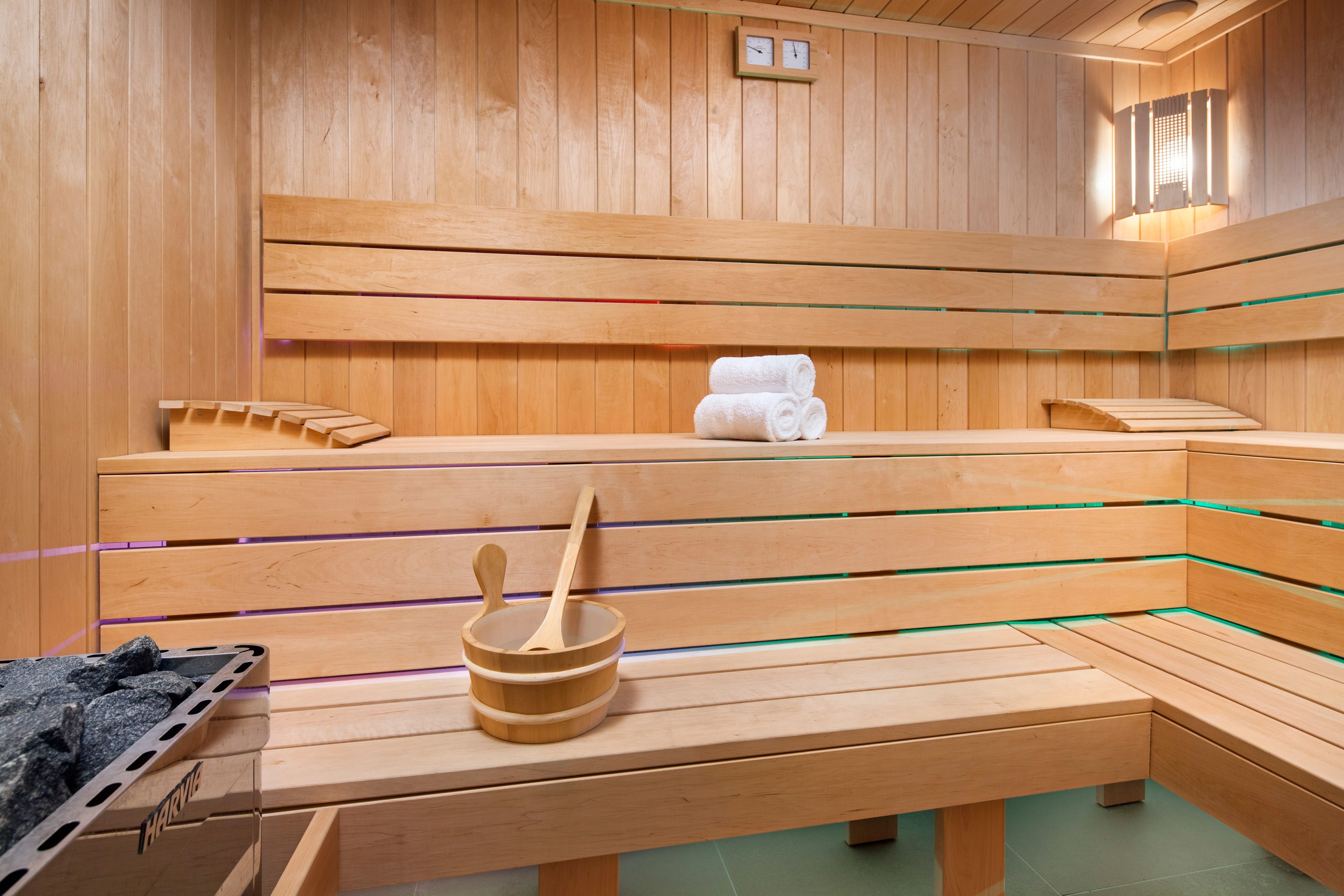 A wooden sauna with benches, a bench with towels, and a wooden bucket with a spoon.