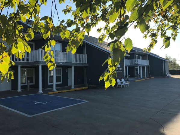 Een gebouw met een overdekt terras, een parkeerplaats voor mindervaliden en een bordje met 