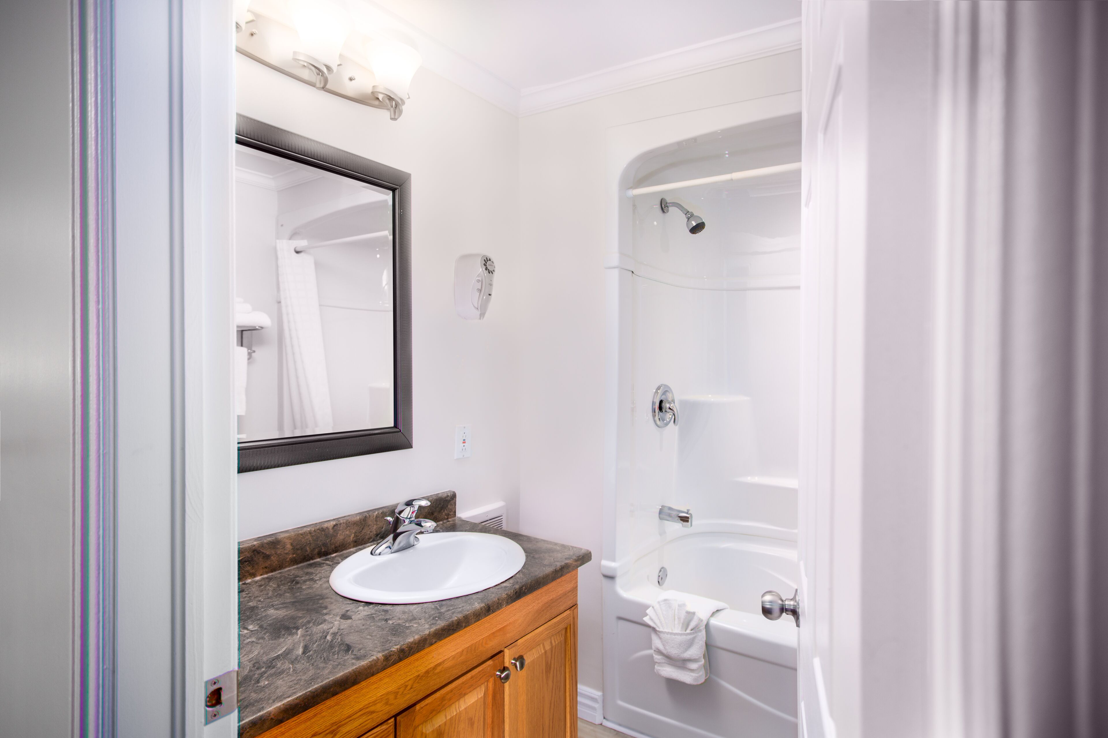 A bathroom with a white sink, wooden vanity, and a white bathtub.