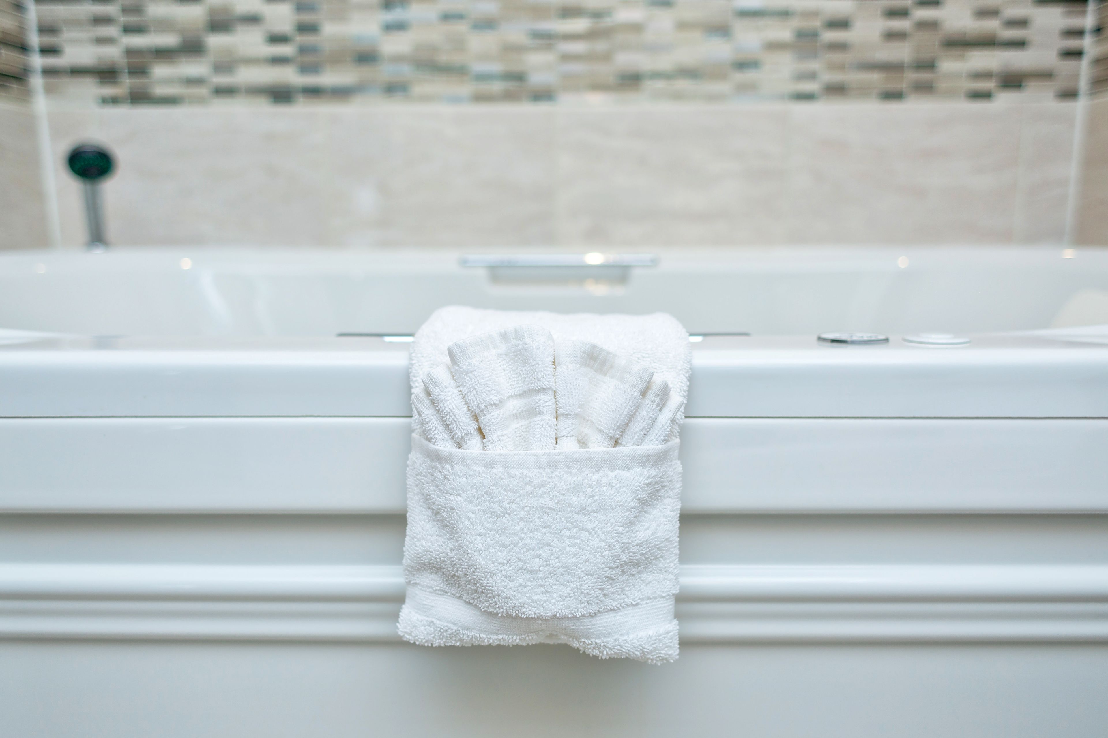 A white bathtub with a white towel hanging over the edge.