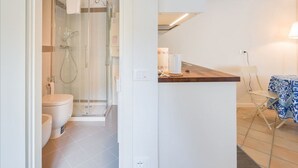A modern bathroom with a glass-enclosed shower, a toilet, and a sink area with a wooden countertop. - Suite del Doge 2 (Verona)