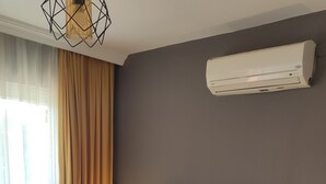 A hotel room with a bed, a nightstand, a lamp, an air conditioning unit, and a window with curtains. - Nostalgia World Boutique Hotel (Manavgat)