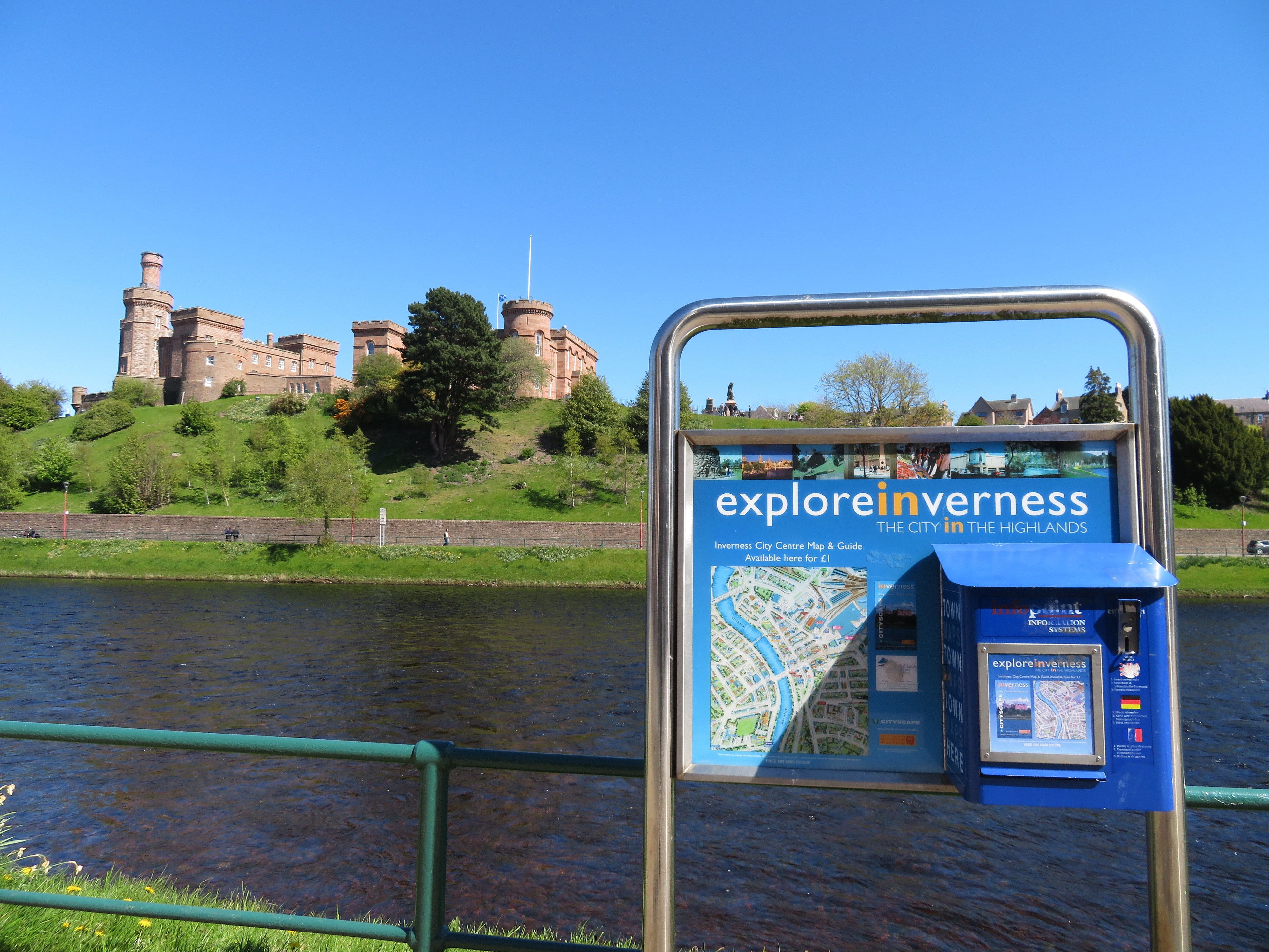 Un expositor con un mapa y guía del centro de la ciudad, con un edificio histórico al fondo.