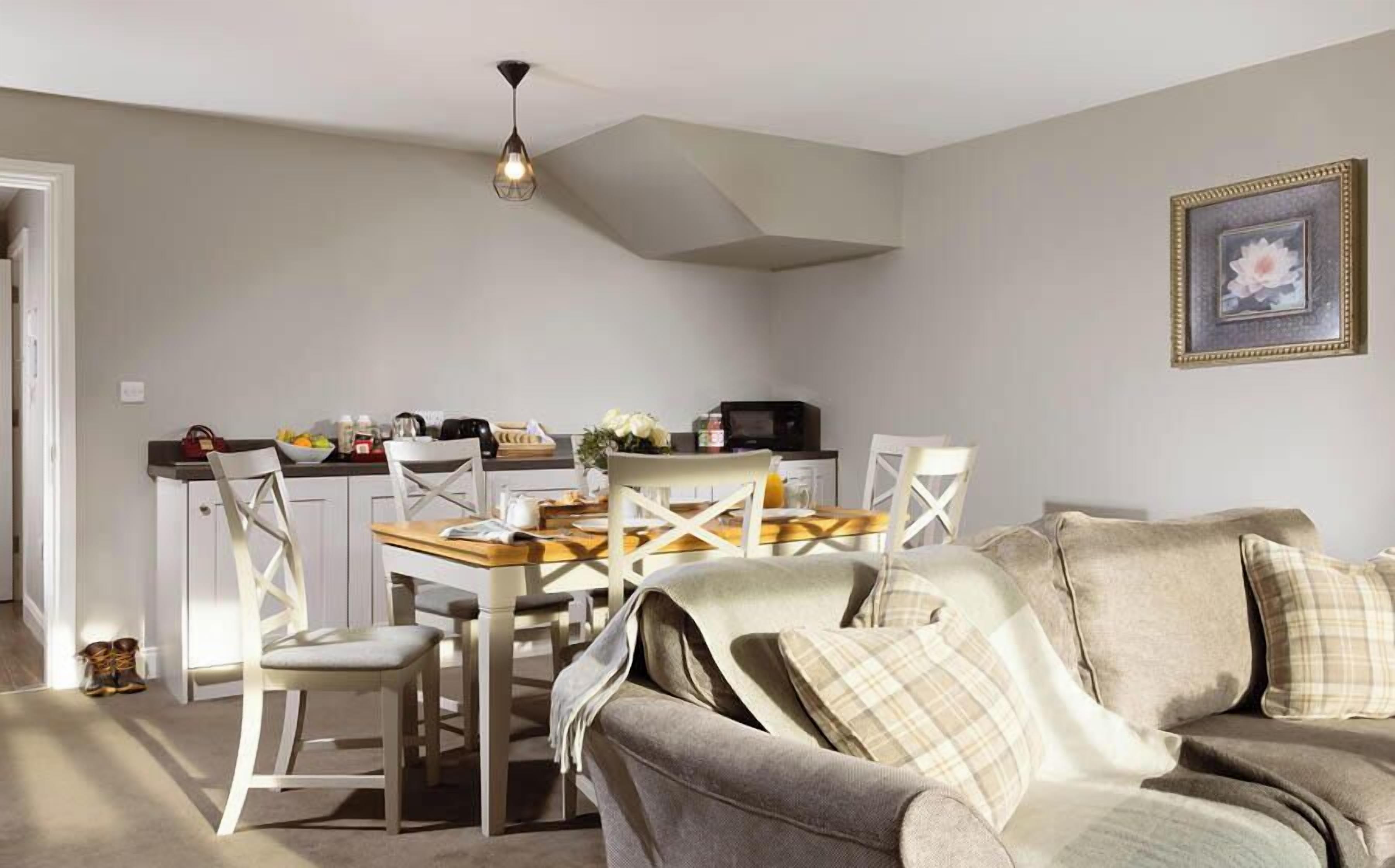 A cozy living room with a sofa, a dining table with chairs, and a kitchen area in the background.