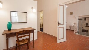 A room with a wooden desk, a chair, a mirror, and a door leading to another room. - Suite Elda (Verona)