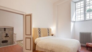 A bedroom with a bed, a radiator, and a window with bars. - Suite Elda (Verona)