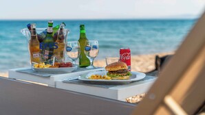 A beachside table with a burger, fries, and drinks, overlooking the ocean. - Assos Park Hotel (Ayvacik)