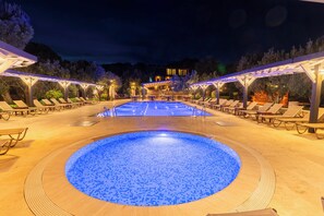 A swimming pool with a blue mosaic tile design, surrounded by lounge chairs and covered seating areas, under a night sky. - Assos Park Hotel (Ayvacik)