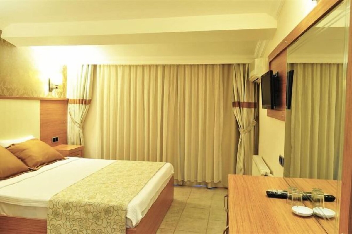 A hotel room with a bed, a desk with a mirror, and a television.
