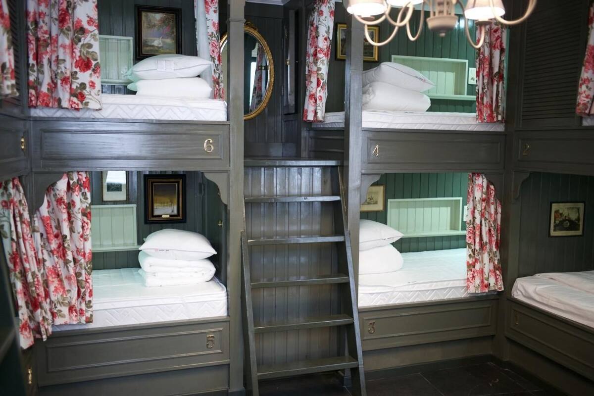 A bunk bed room with floral curtains, a ladder, and a mirror.
