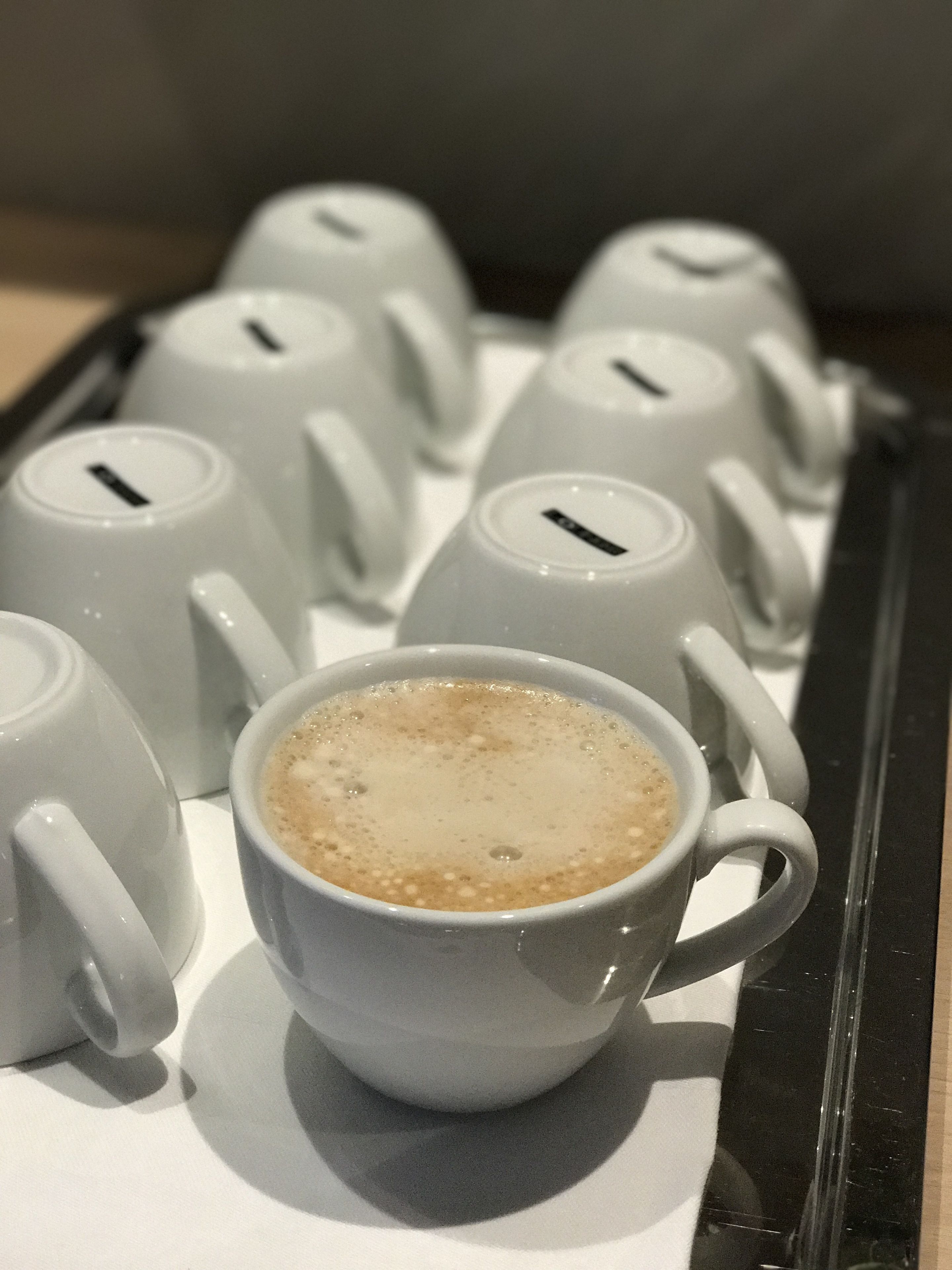 Una bandeja con una taza de café y varios teteras blancas.