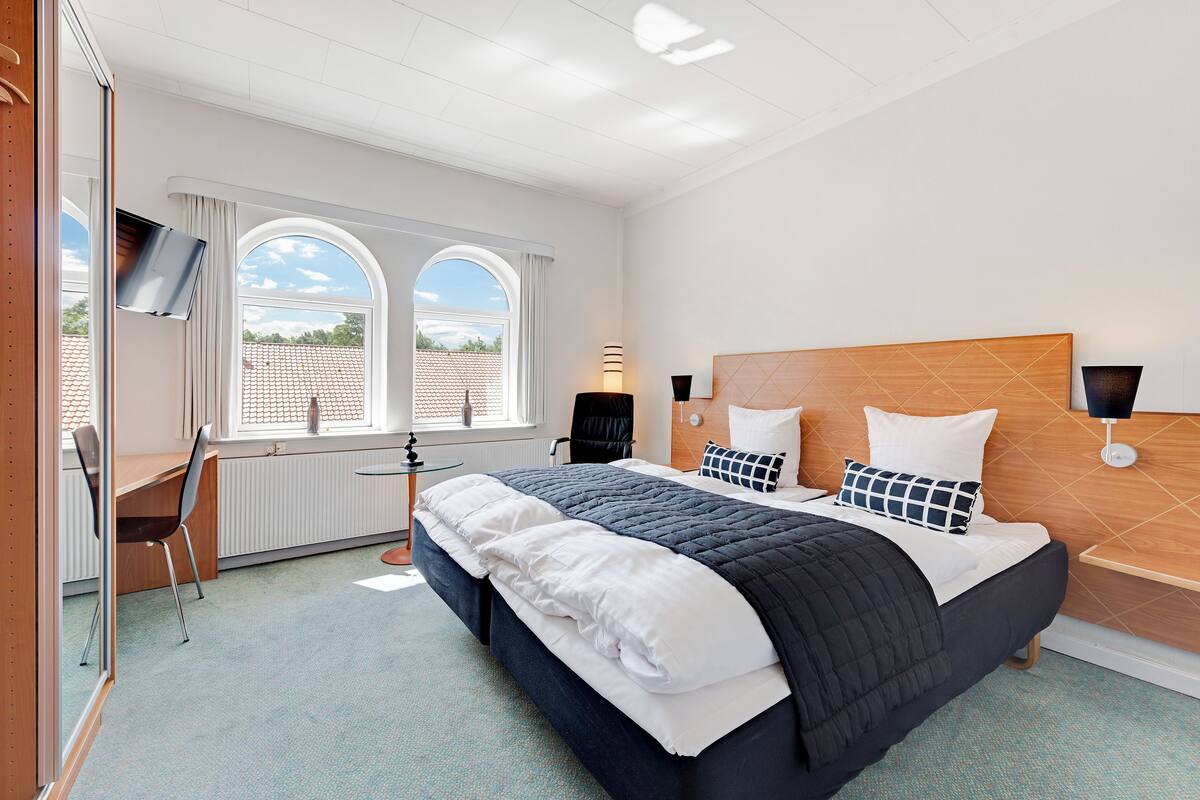 Une chambre d’hôtel avec un grand lit, un bureau et une télévision.