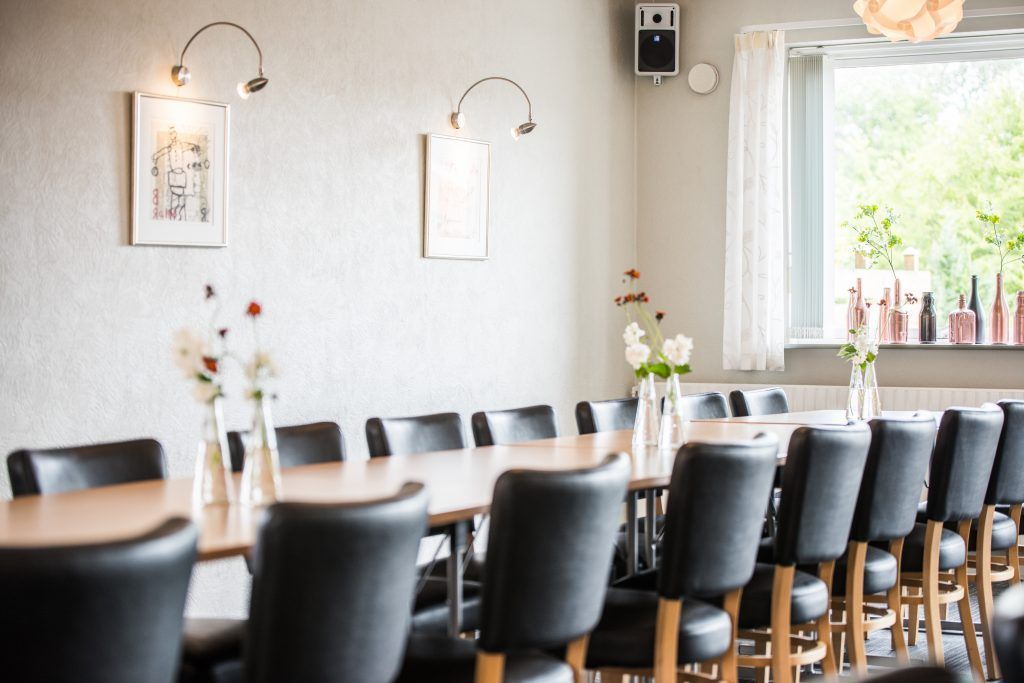 En matplats med ett långt bord, svarta stolar och inramade konstverk på väggen.