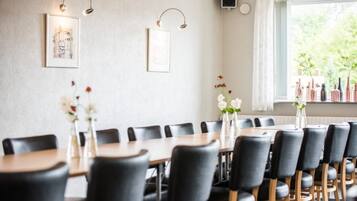 En matplats med ett långt bord, svarta stolar och inramade konstverk på väggen.