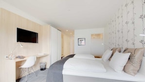 Una habitación de hotel moderna con cama, escritorio, silla y televisor.