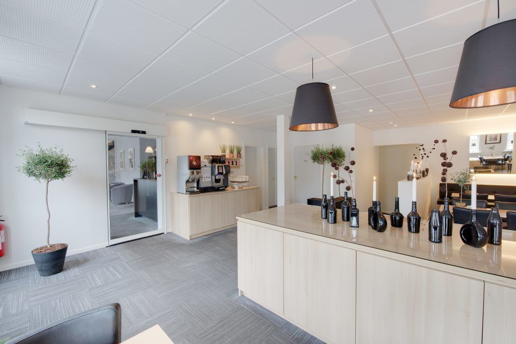 Una cocina moderna con una isla central, iluminación colgante y vista al área de comedor.