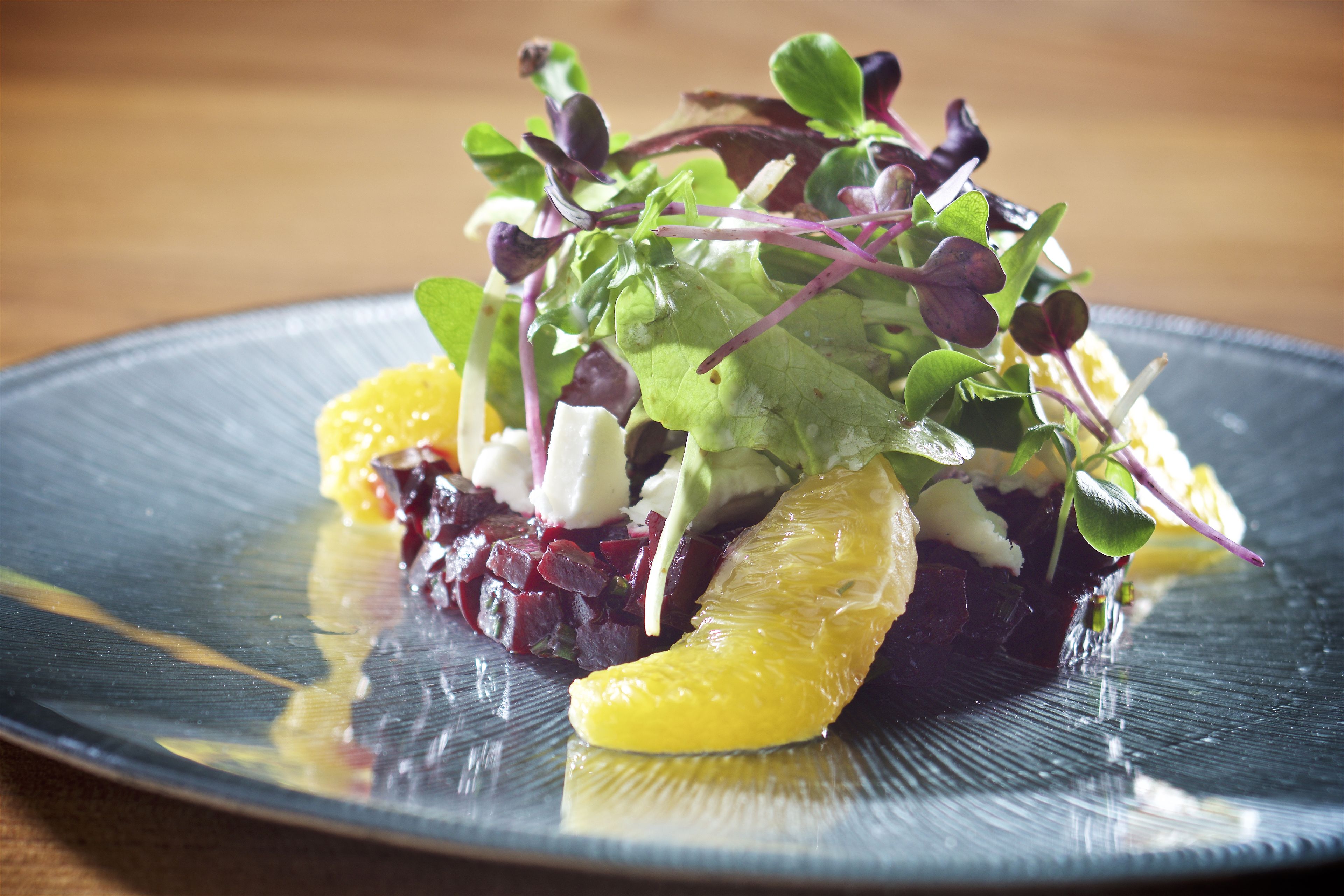 A plate with a salad of mixed greens, beetroot, and orange slices.