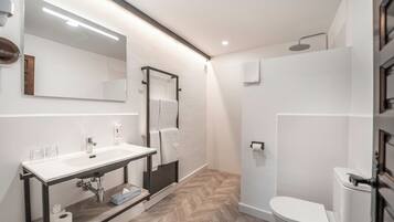 A modern bathroom with a white sink, mirror, and toilet.